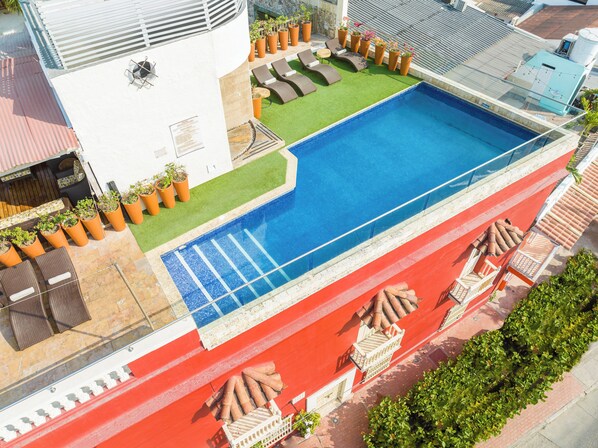 A rooftop pool with a blue mosaic border, surrounded by lounge chairs and potted plants. - GHL Collection ArmerÃa Real Hotel (Cartagena)