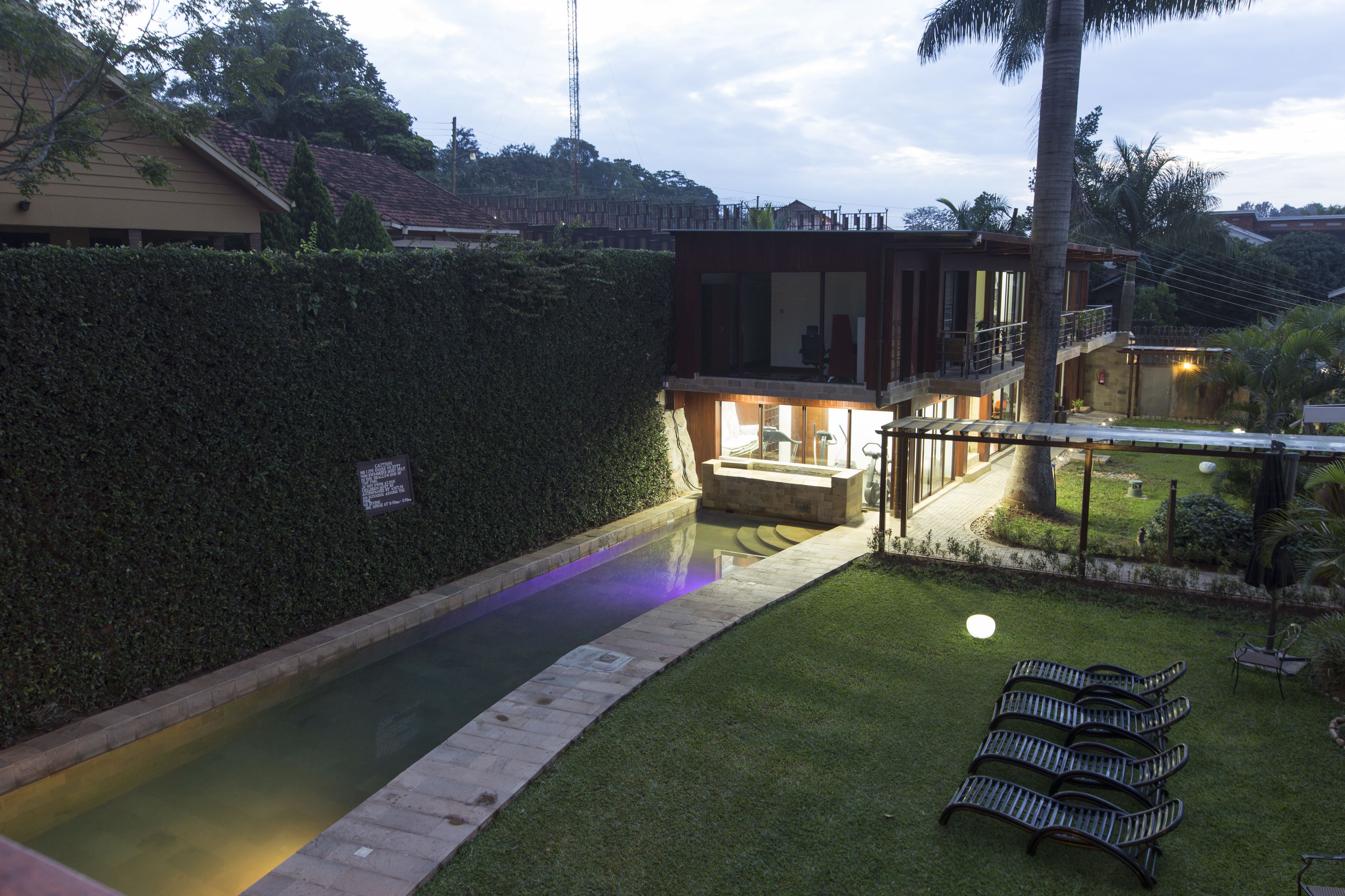 A modern house with a swimming pool, a covered patio, and a well-maintained lawn.