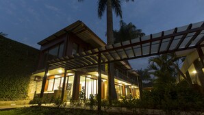 Une maison moderne dotée d’un patio couvert, de grandes fenêtres et d’un intérieur bien éclairé.