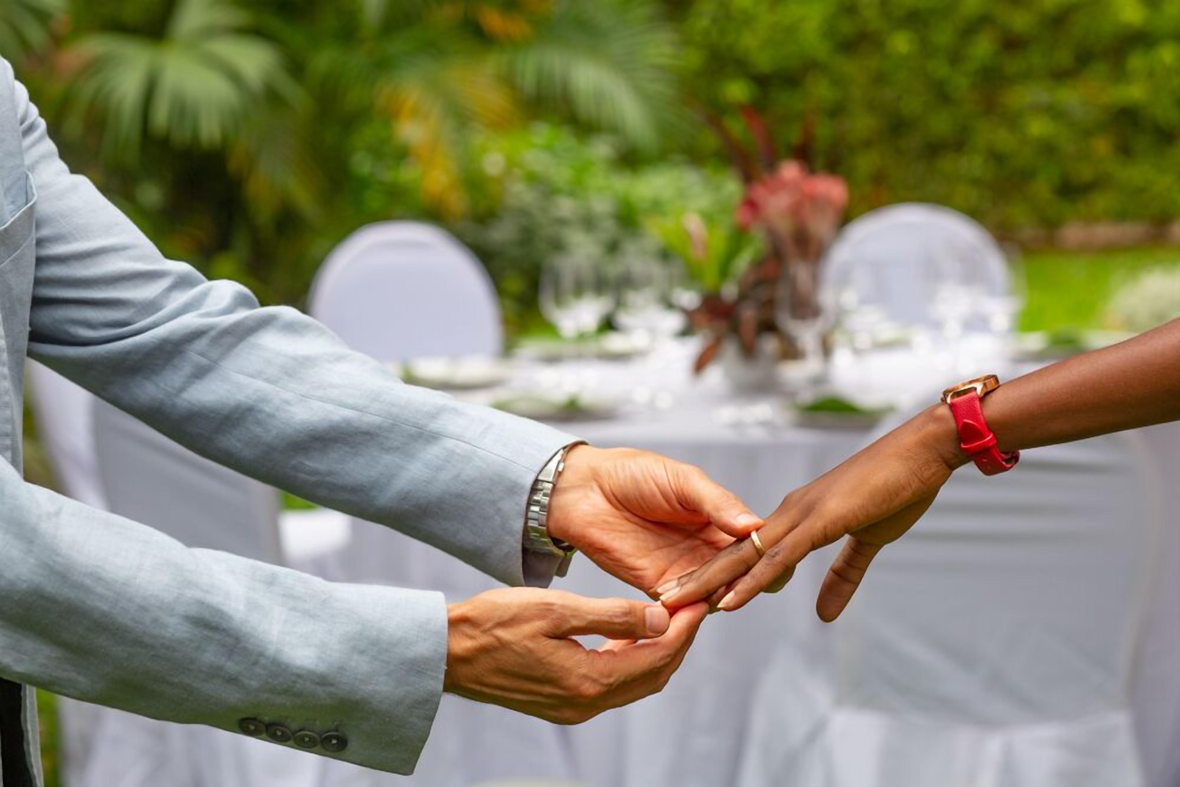 Primer plano de dos manos intercambiando un anillo.