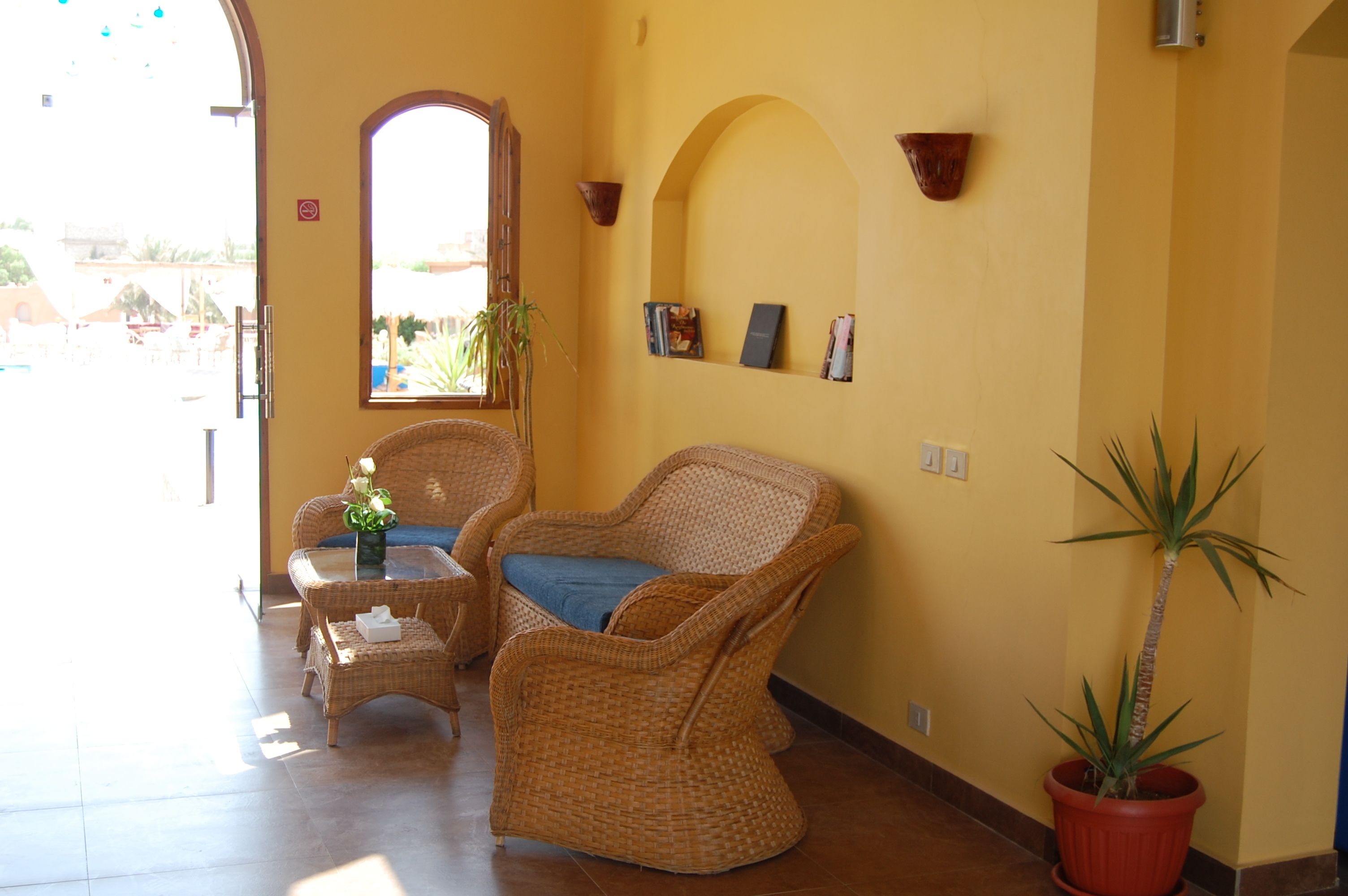 Una habitación con muebles de mimbre, una planta en maceta y vistas al exterior.