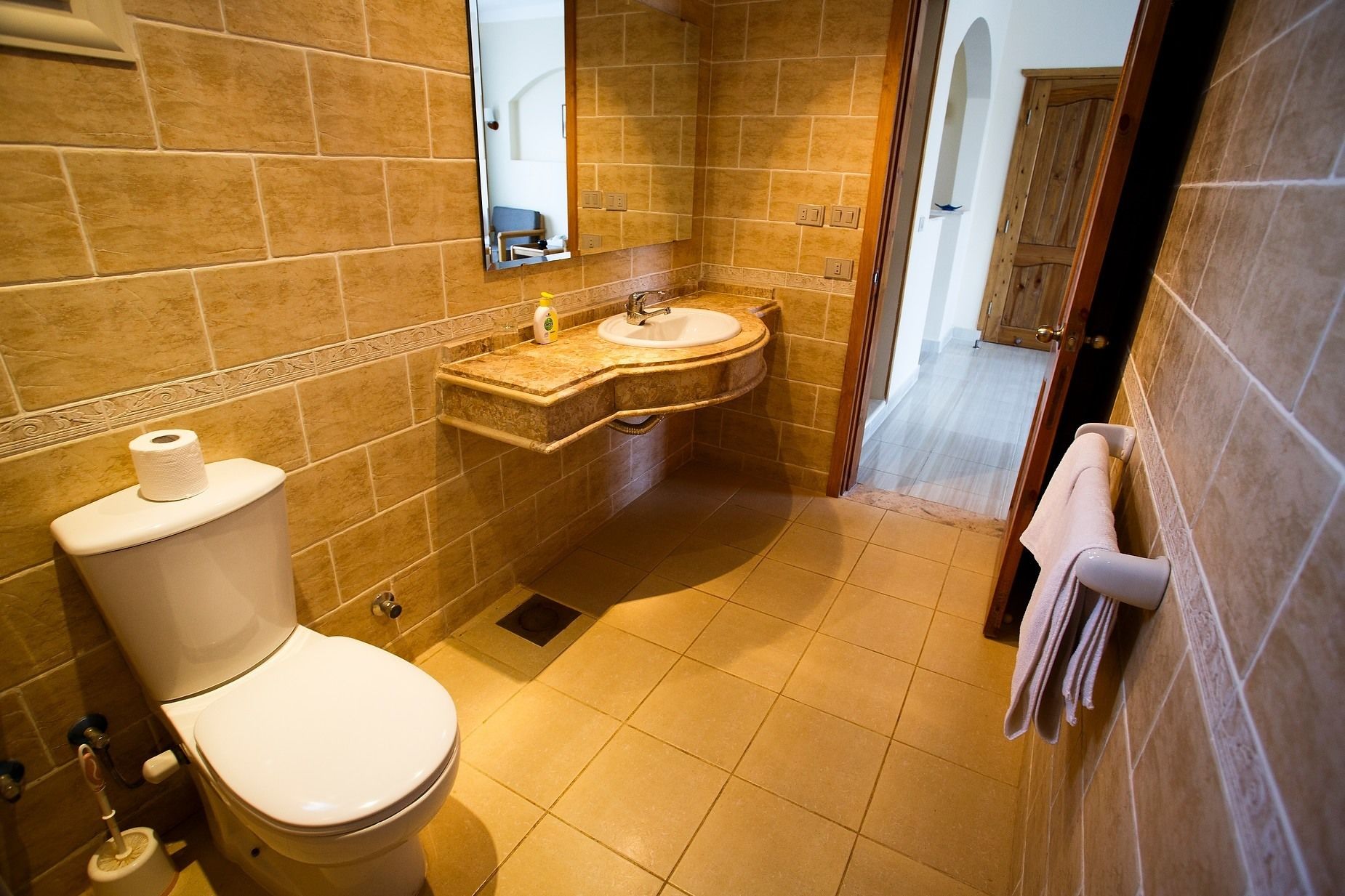 Een badkamer met toilet, wastafel en spiegel.