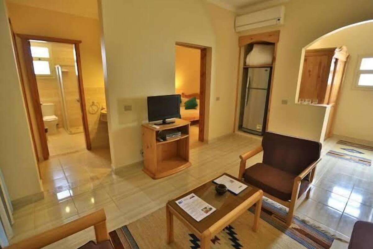 A spacious living room with a wooden coffee table, a television on a stand, and a comfortable armchair.
