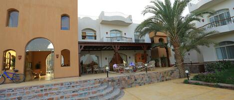Un hotel con patio, zona de estar al aire libre y una palmera.