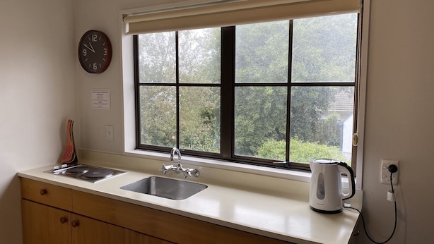 A kitchen with two sinks, a window, a clock, and a kettle. - Southern Comfort Motel (Christchurch)
