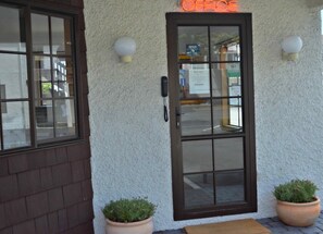 A building entrance with a glass door, a sign reading "OFFICE", and two potted plants. - Southern Comfort Motel (Christchurch)