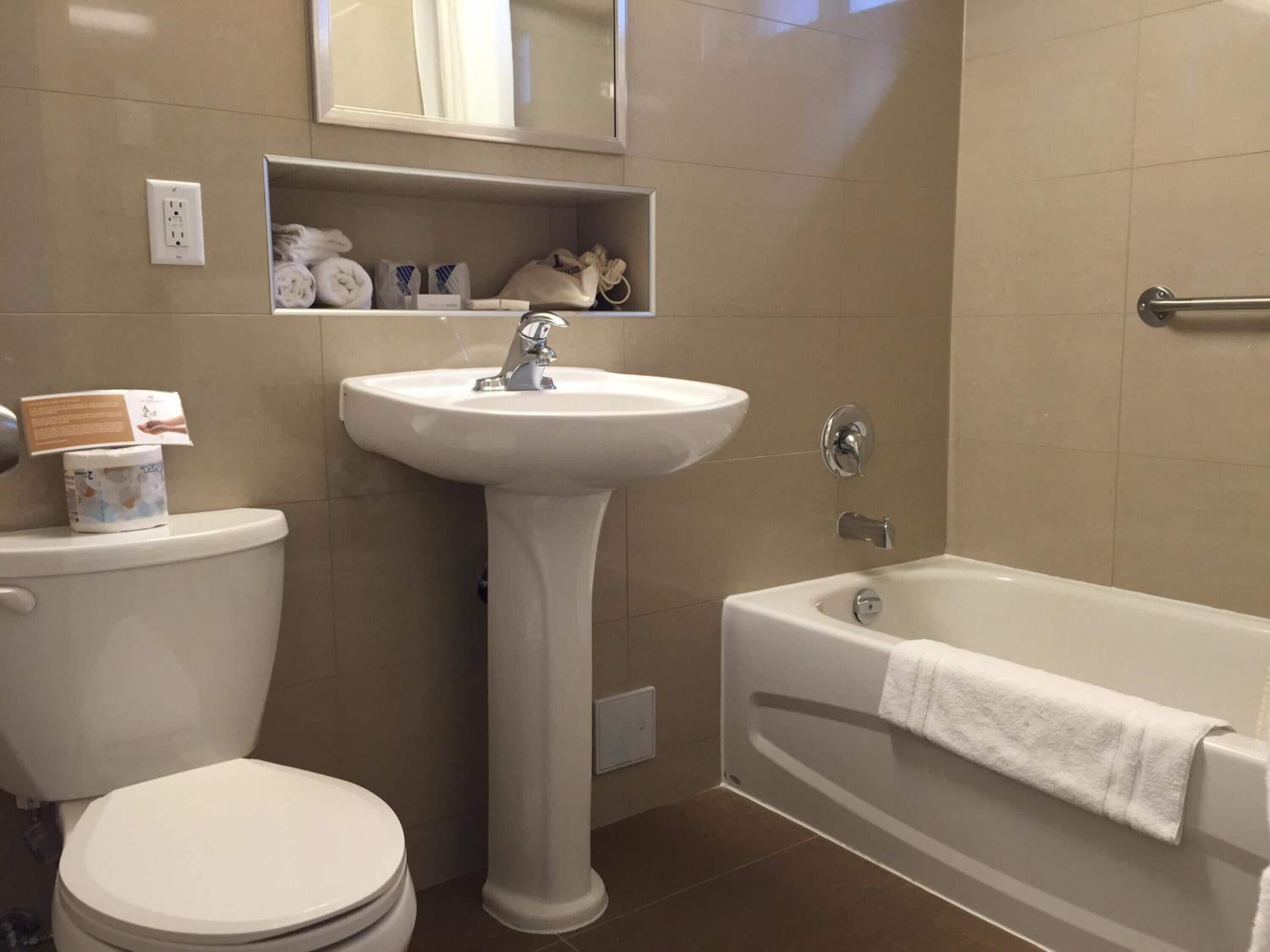 A bathroom with a pedestal sink, toilet, and bathtub.