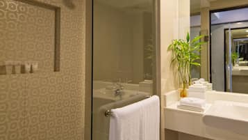 Un baño moderno con ducha envuelta en vidrio, un lavabo blanco y un espejo sobre el mostrador.