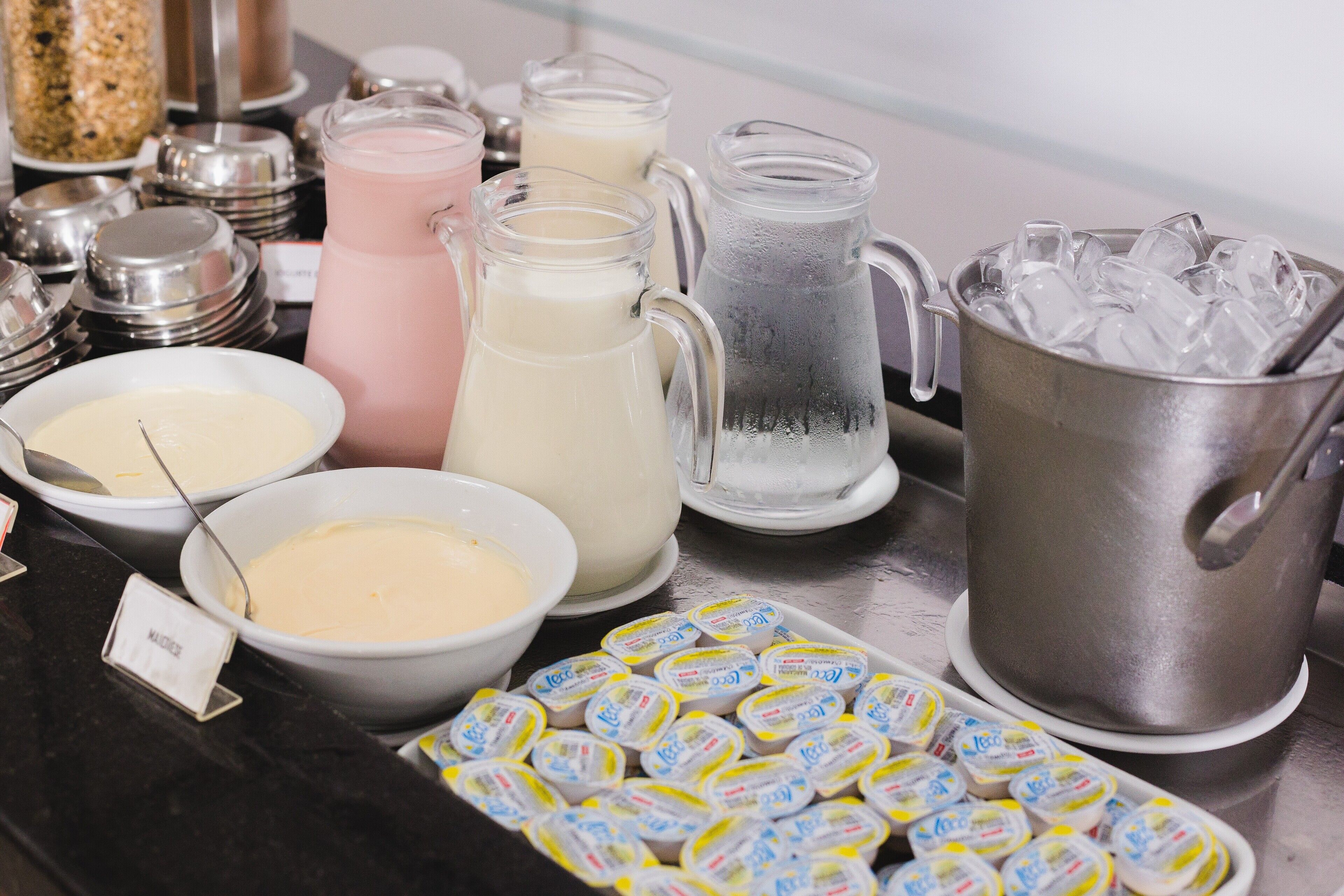 A buffet with various food and drink options, including pitchers of milkshakes, bowls of dip, and containers of yogurt.