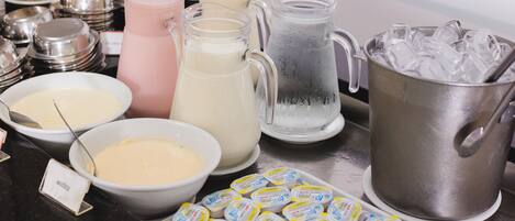 A buffet with various food and drink options, including pitchers of milkshakes, bowls of dip, and containers of yogurt.