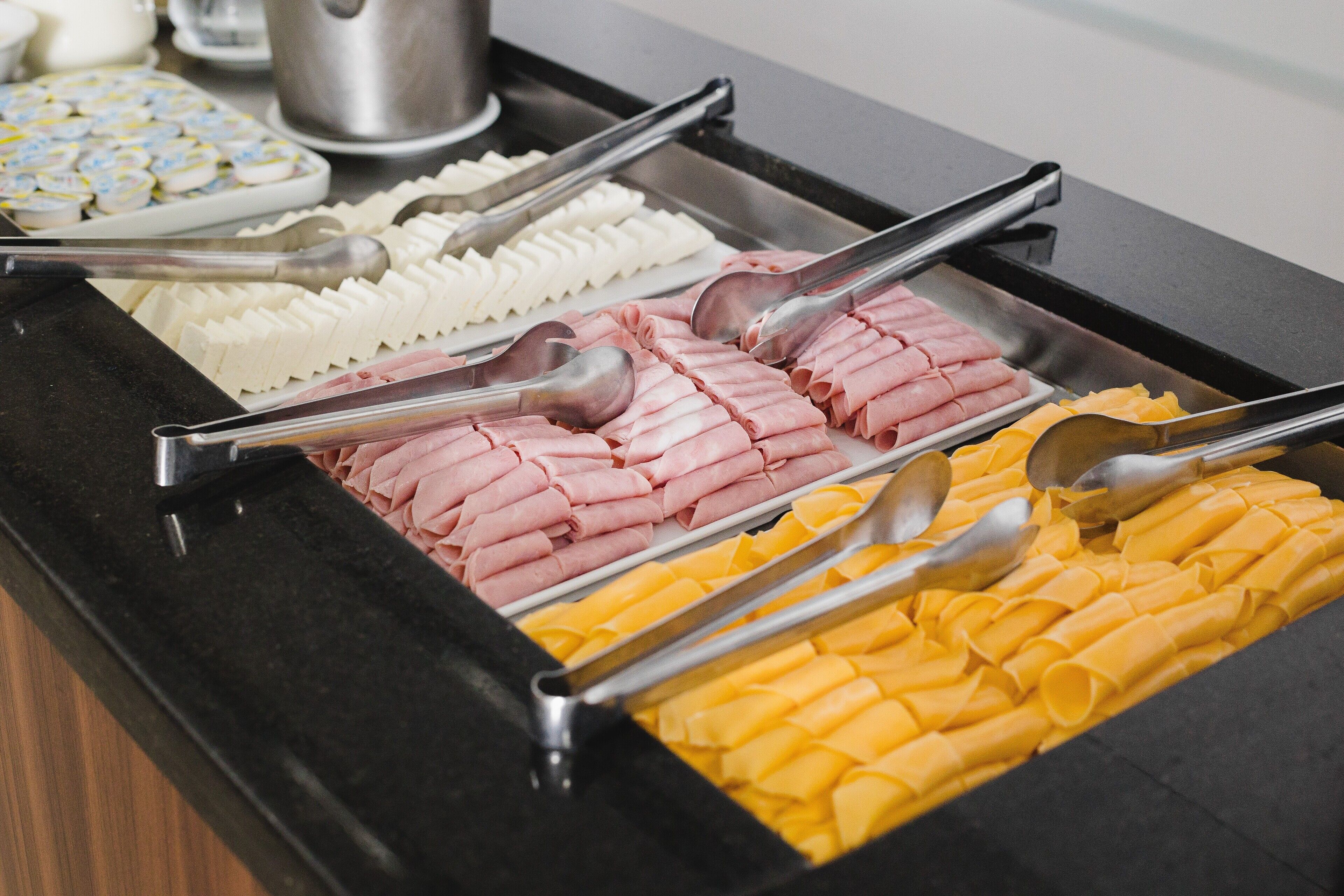 A buffet with various food items including white, pink, and yellow sections, each with serving utensils.