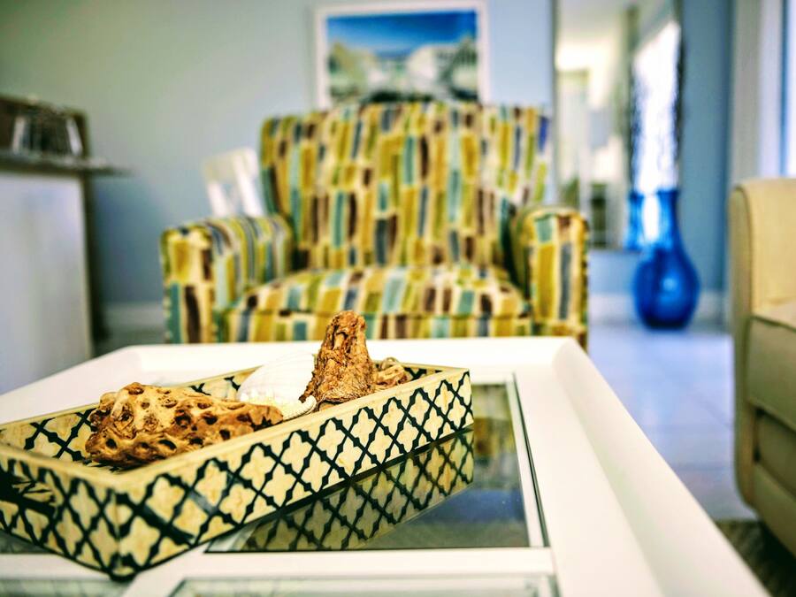 A living room with a patterned armchair, a coffee table with a decorative object, and a vase.