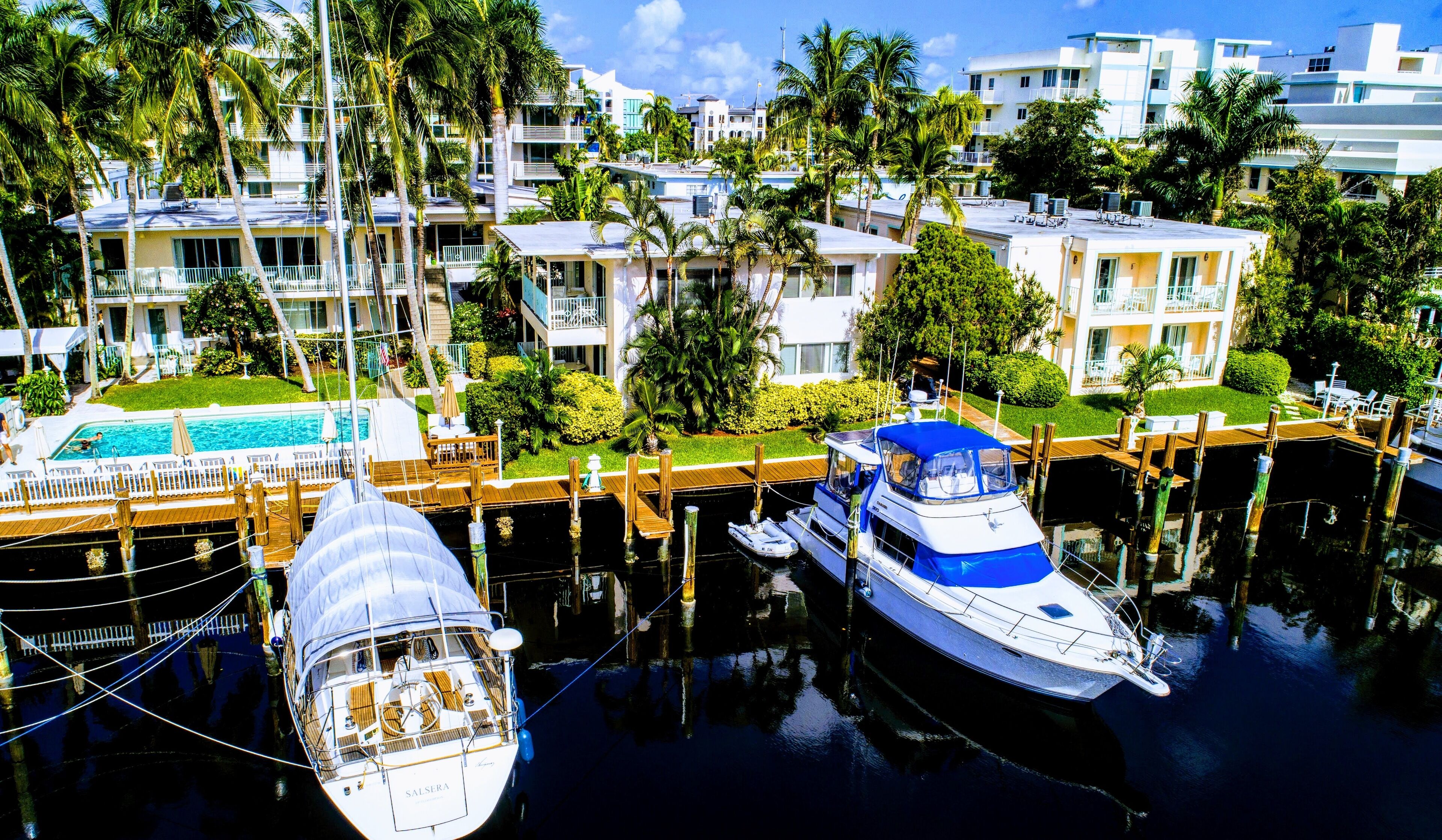 A marina with boats docked, a swimming pool, and a building with balconies.