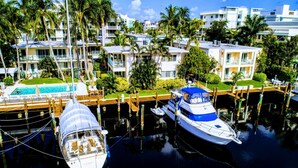 A marina with boats docked, a swimming pool, and a building with balconies. - Villa Venezia (Fort Lauderdale)