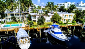 A marina with boats docked, a swimming pool, and a building with balconies. - Villa Venezia (Fort Lauderdale)