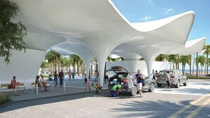 Un espacio exterior moderno con toldos blancos, palmeras y gente caminando.