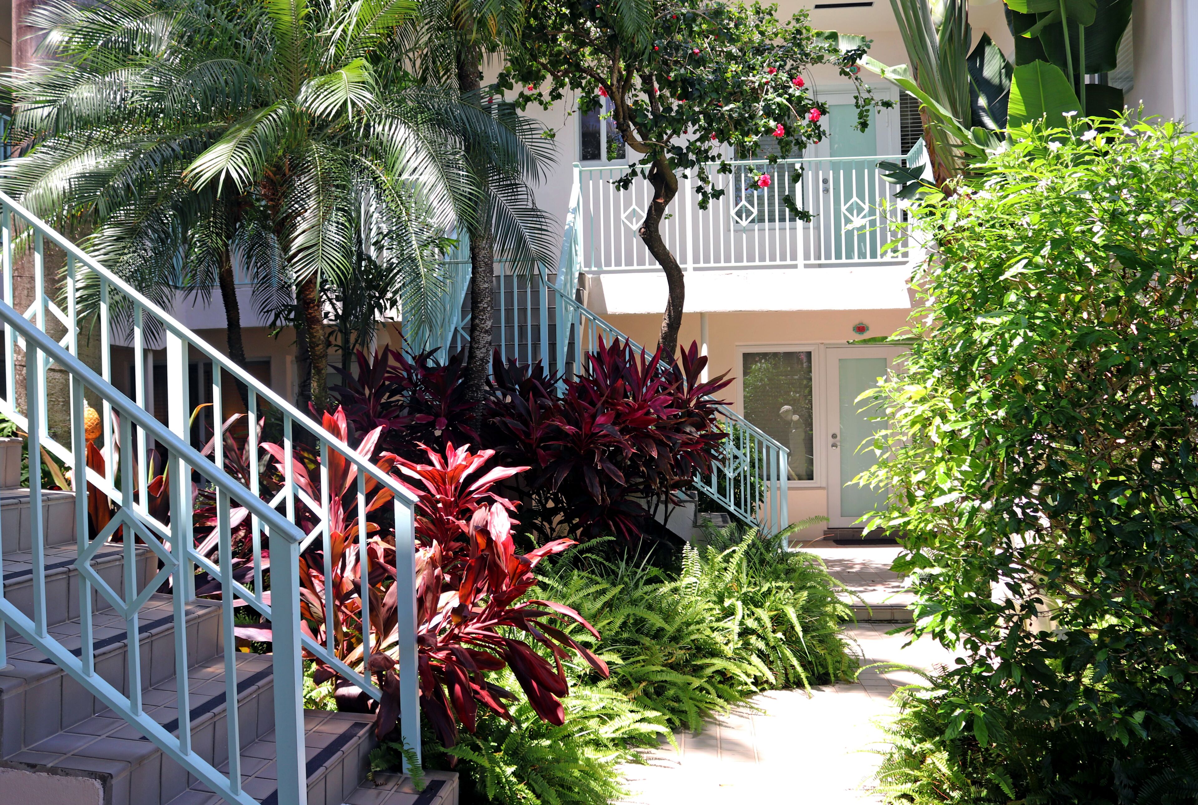 A staircase with a metal railing leading to a building with a balcony.