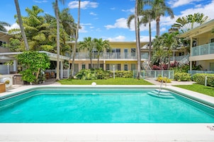 A swimming pool surrounded by palm trees and a building with balconies.