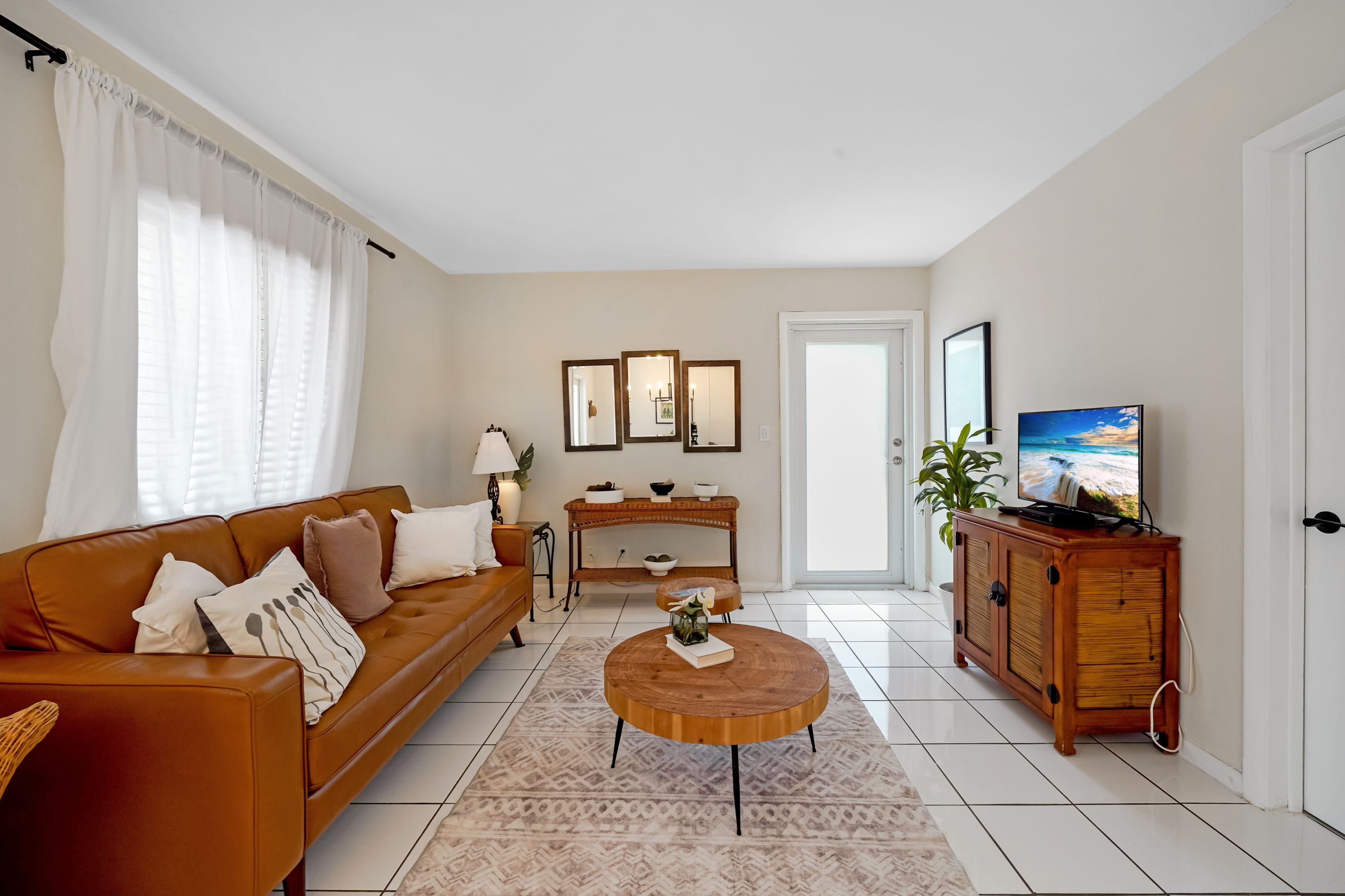 A living room with a brown leather sofa, a coffee table, a television, and a cabinet.