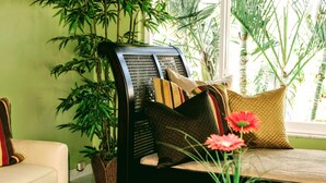 A room with a sofa, a chair with a woven backrest, and a large potted plant. - Villa Venezia (Fort Lauderdale)