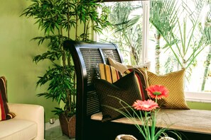A room with a sofa, a chair with a woven backrest, and a large potted plant. - Villa Venezia (Fort Lauderdale)