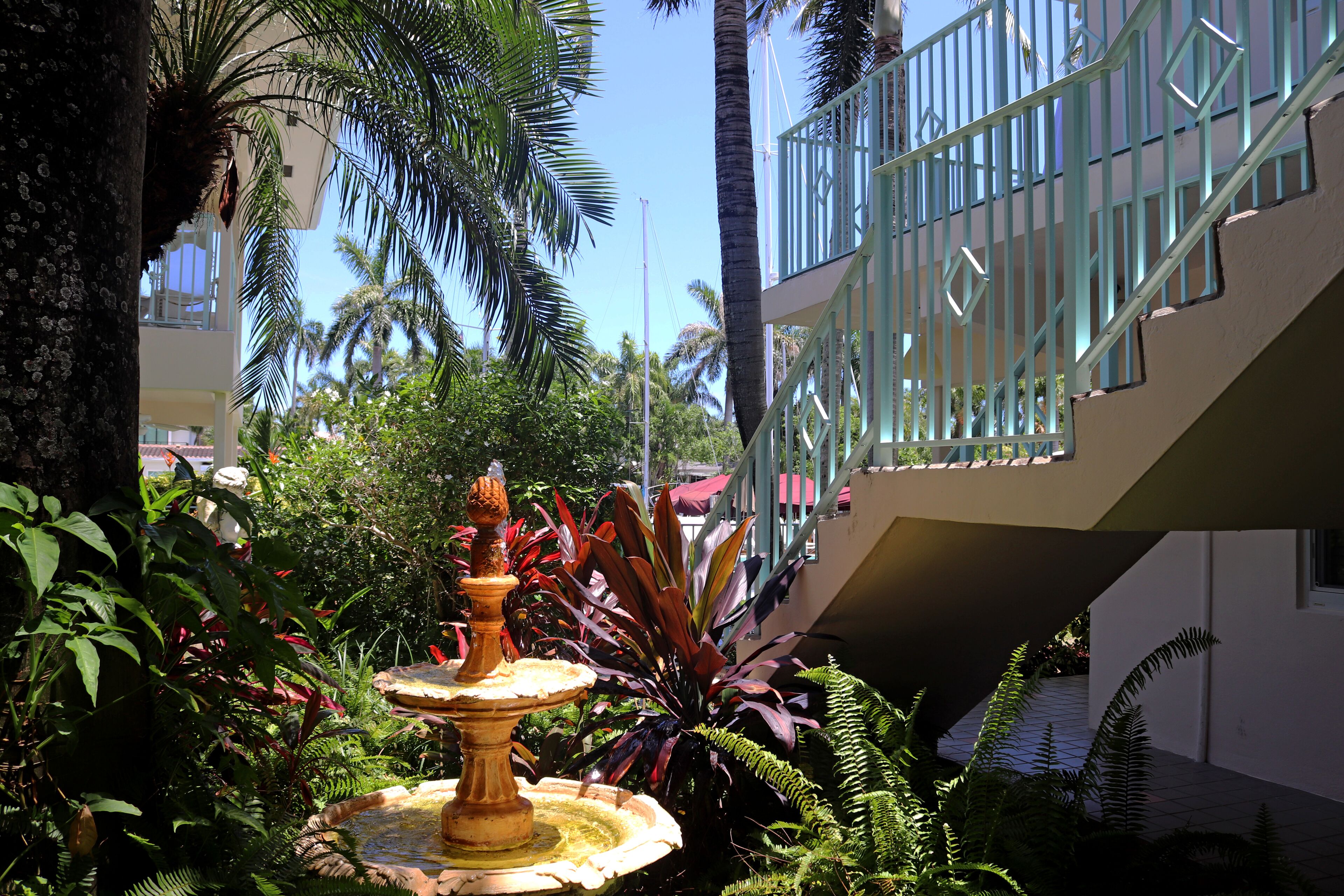 Une cour avec une fontaine, des palmiers et un bâtiment doté d’un balcon.
