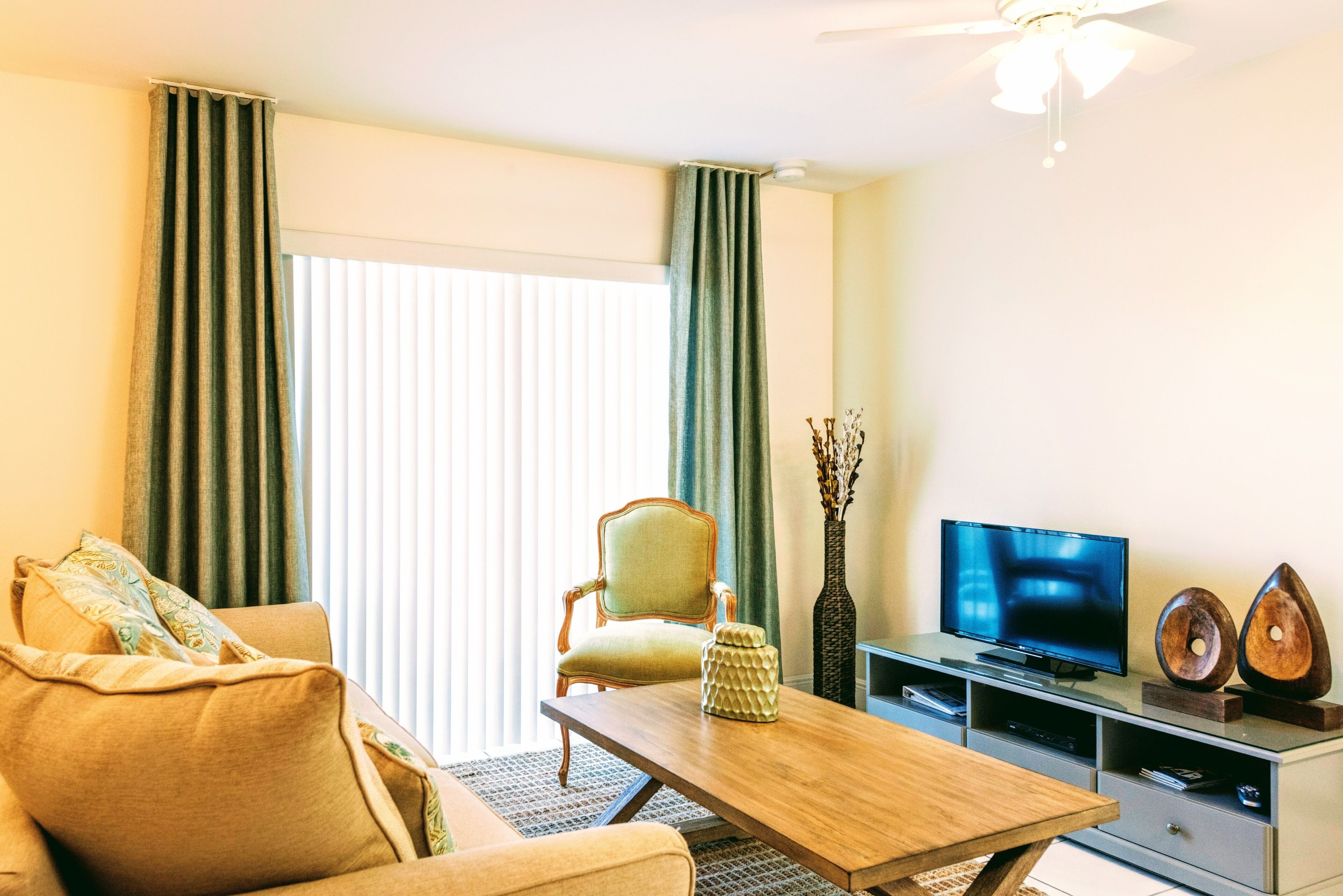 A living room with a sofa, armchair, coffee table, TV, and decorative items.