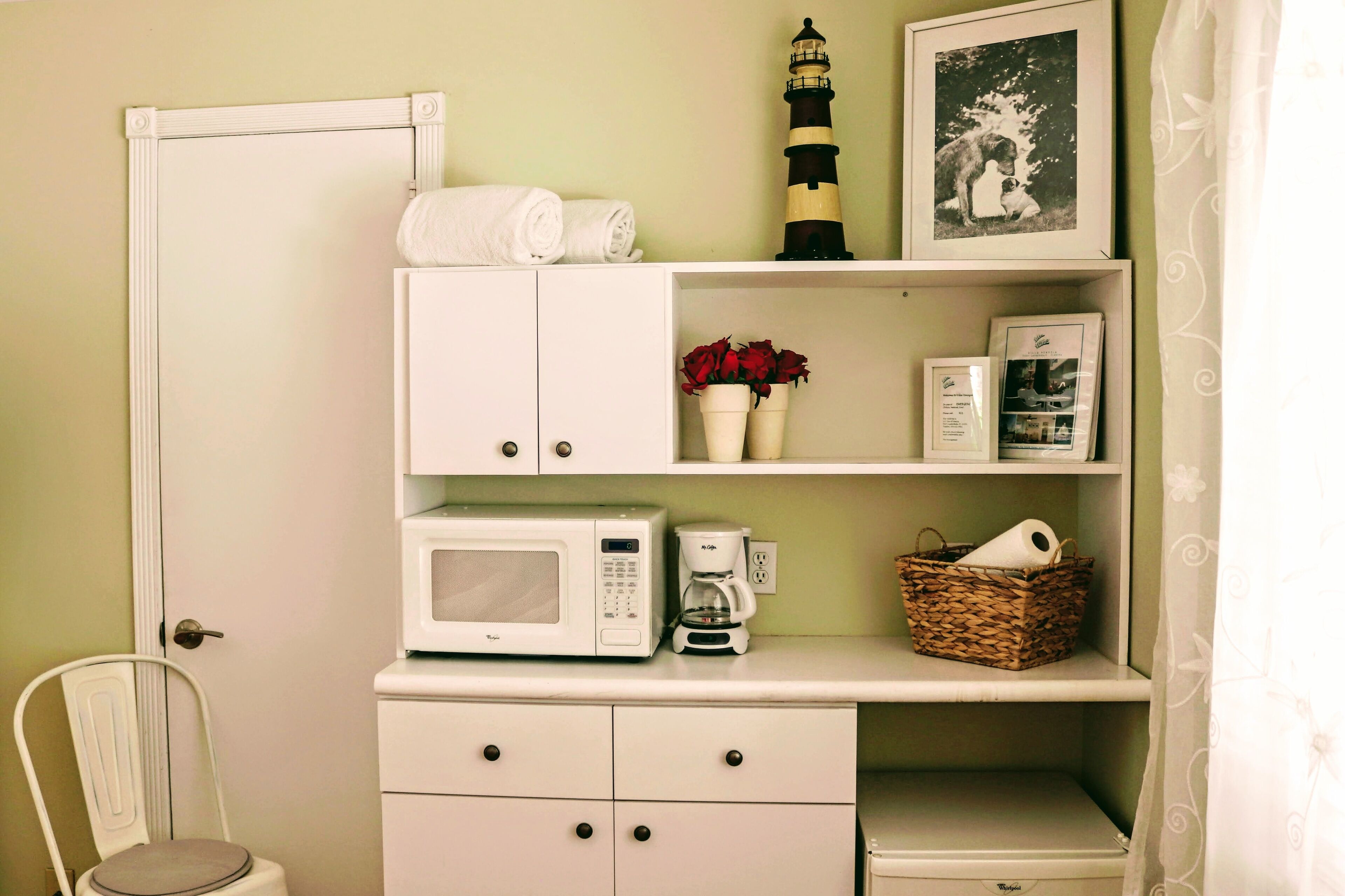 A kitchenette with a microwave, coffee maker, and a basket on the countertop.