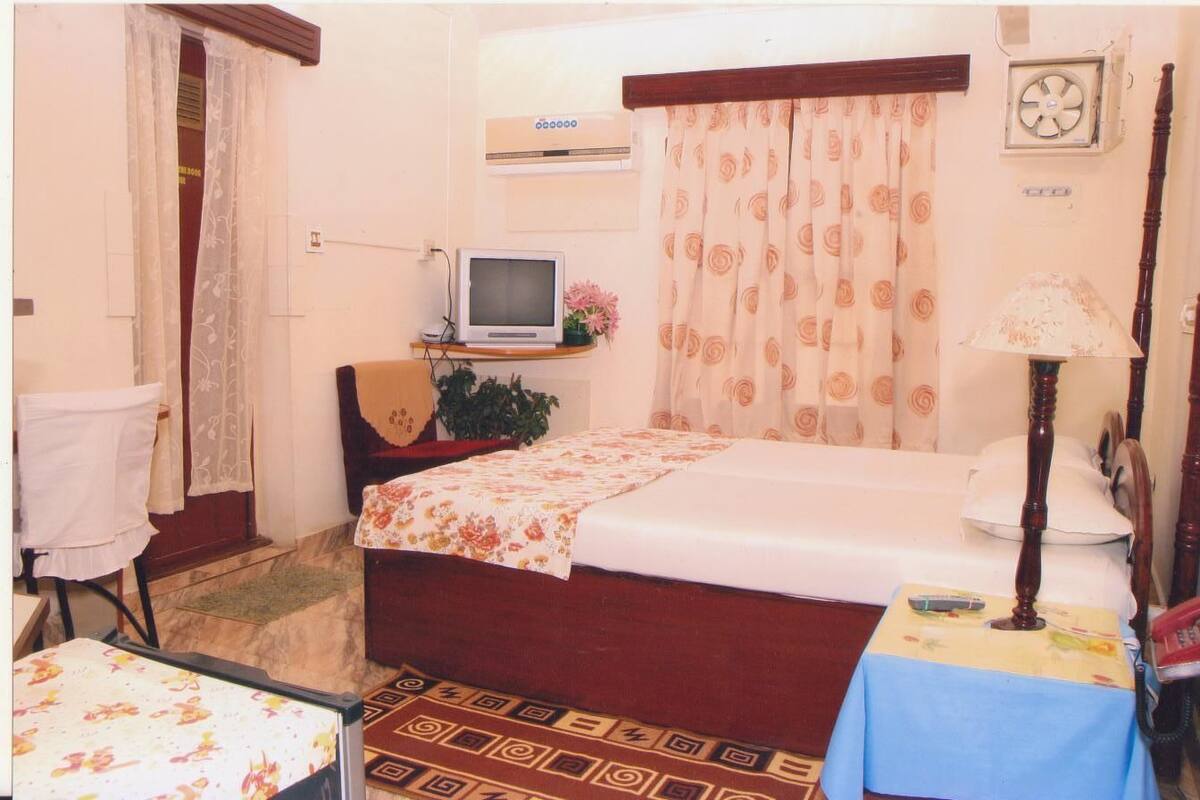 A small, cozy room with a bed, a television, a desk, and a chair.
