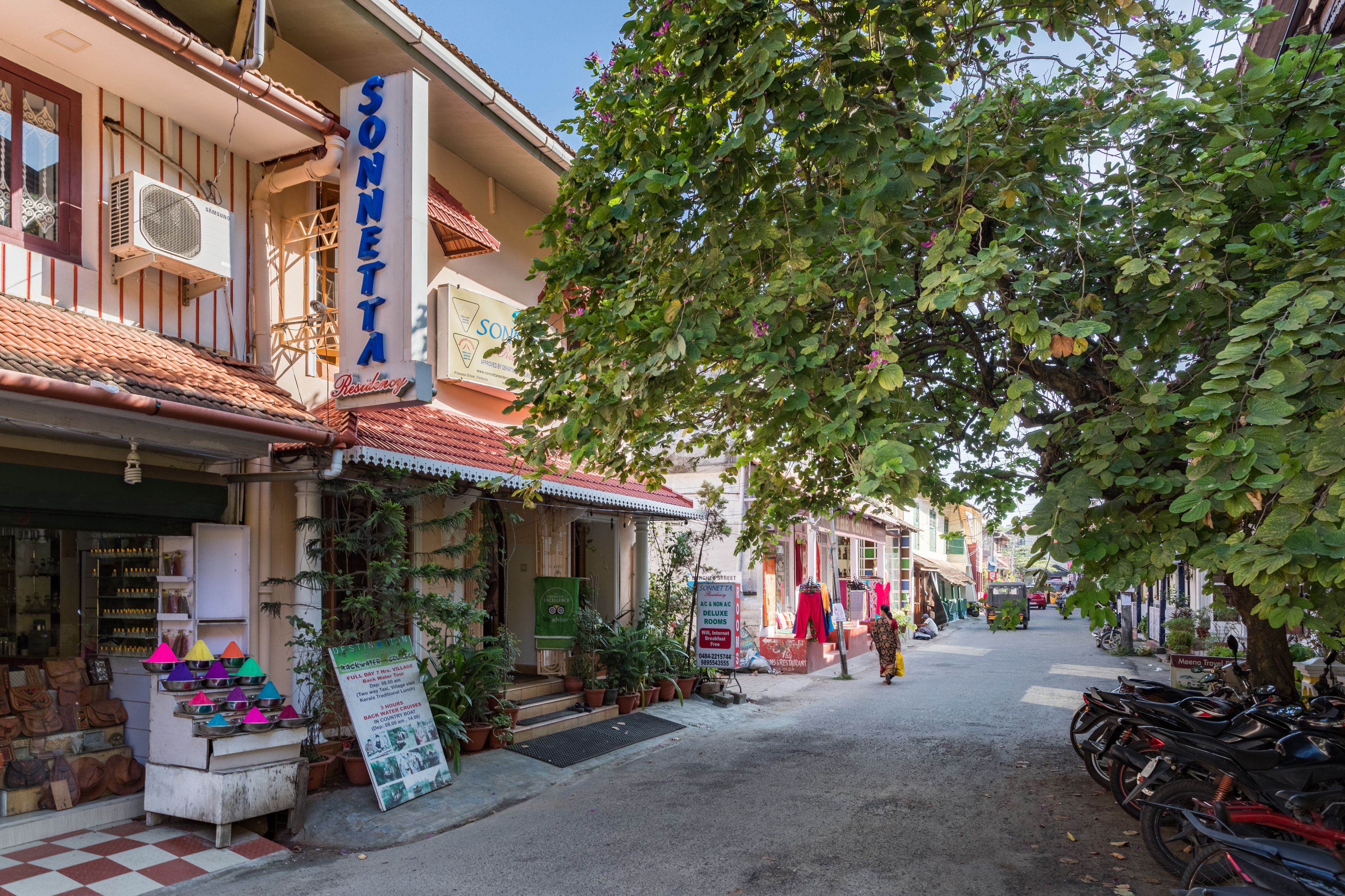 Une vue de rue avec un bâtiment portant l’inscription « SONNETTA » et un panneau indiquant qu’il propose des chambres à louer.
