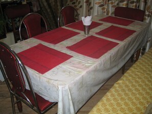 A dining table with a red table runner, a vase with a white napkin, and metal chairs.