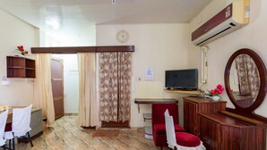 A hotel room with a bed, a TV, a desk with a chair, a wardrobe, and a mirror. - Sonnetta Residency (Kochi)
