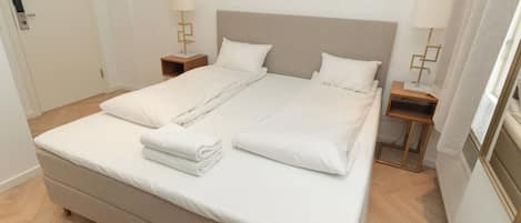 A double bed with a headboard, two bedside tables with lamps, and a wooden floor.