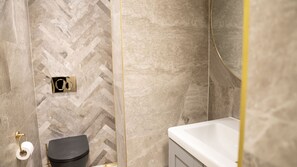 Un bagno con pavimento a motivo a spina di pesce, un WC e un lavandino bianco.