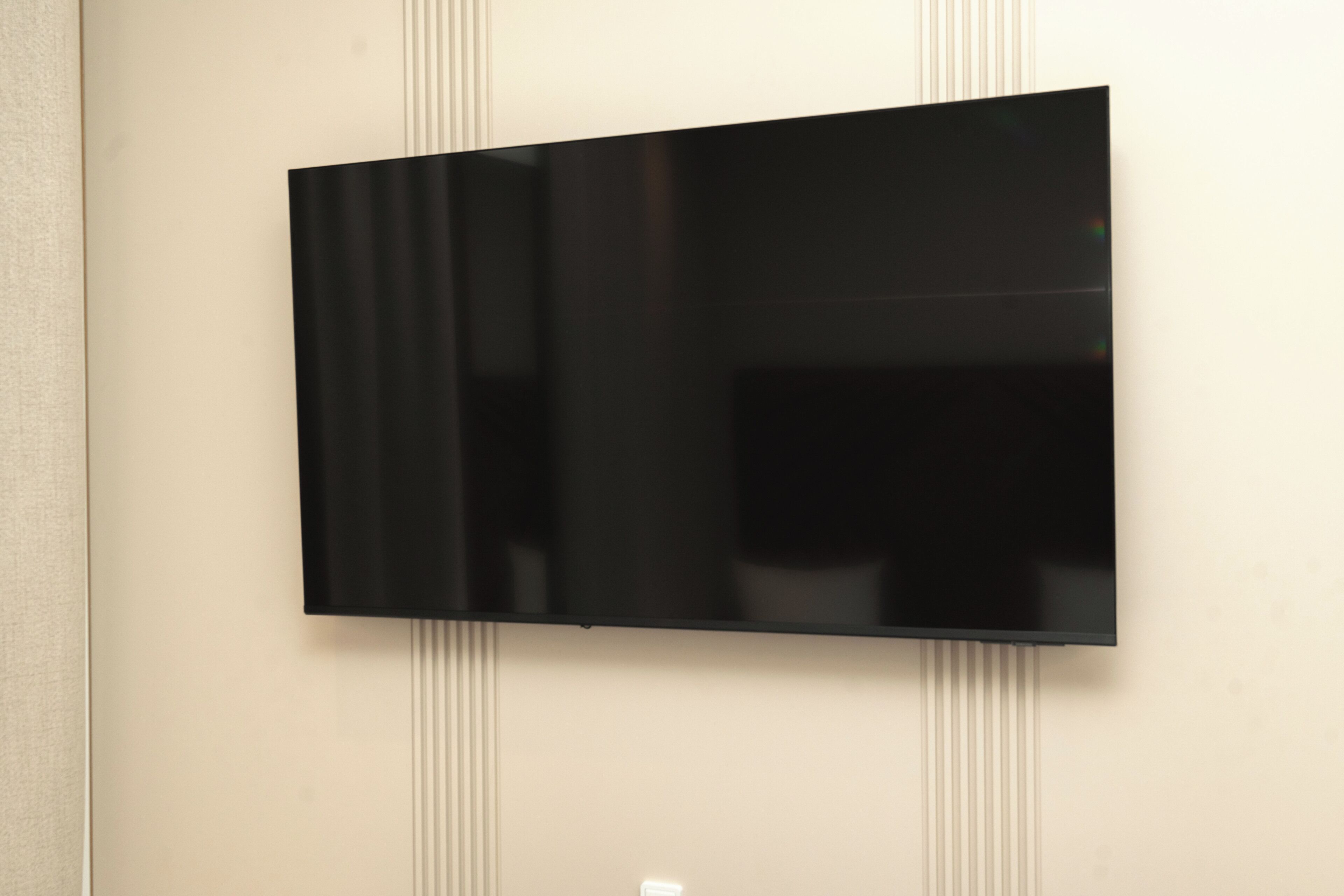 A flat-screen TV mounted on a wall with vertical paneling.