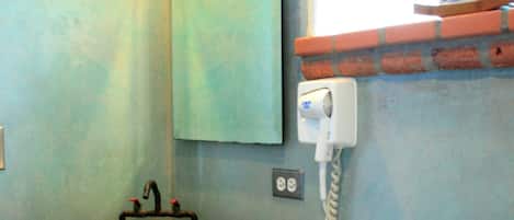 Un baño con lavabo de cerámica, un espejo, una toalla y un teléfono.