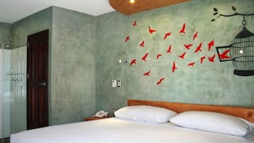 A hotel room with a bed, a wooden headboard, a nightstand with a phone, and a wall with red bird decals.