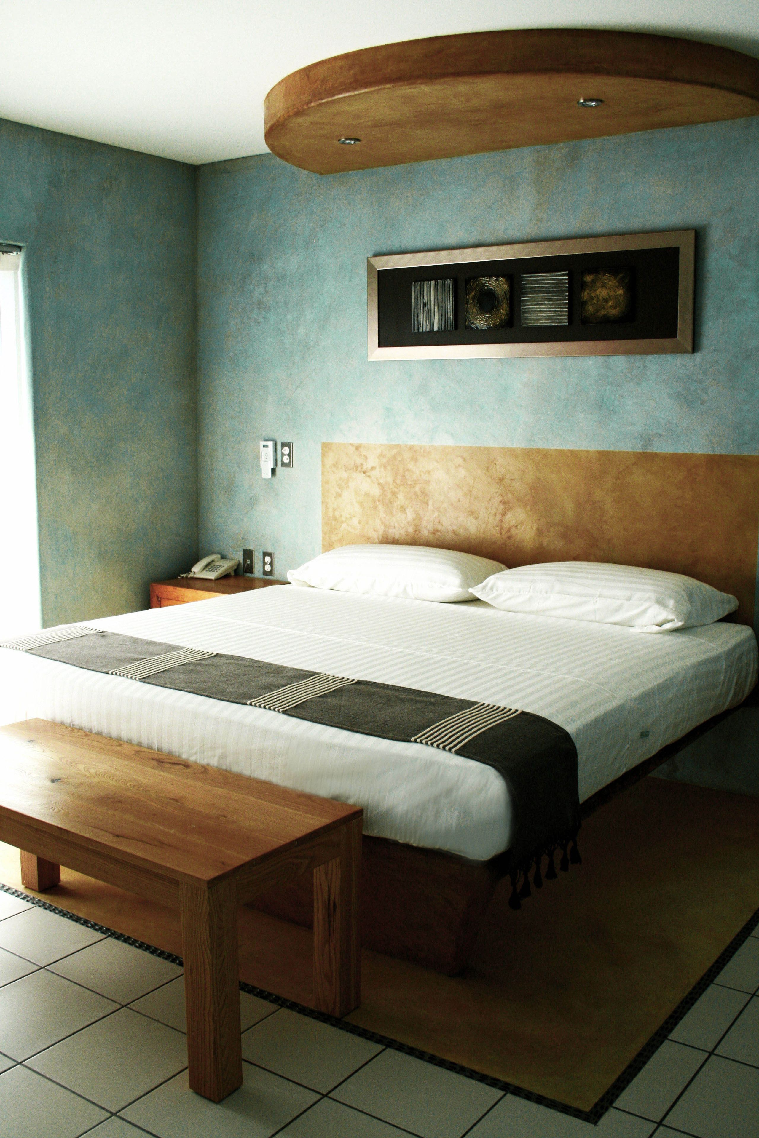 A bedroom with a bed, bedside table, and a wooden bench.