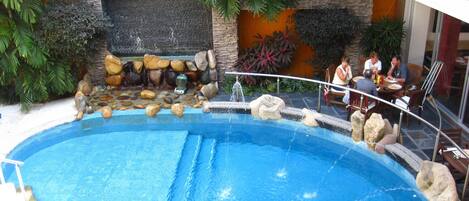 Una piscina interior con una cascada, rodeada de rocas y plantas.