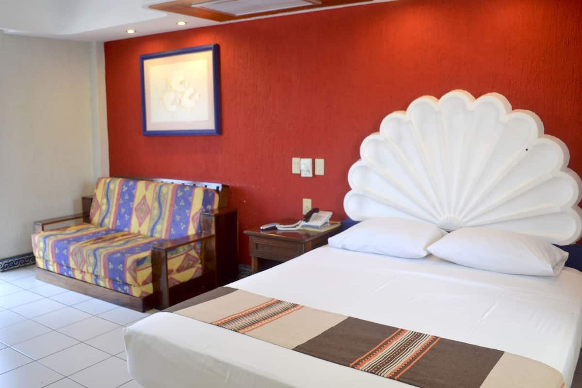 A hotel room with a bed, a chair, a nightstand, and a wall-mounted telephone.