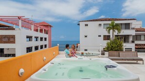 A rooftop with a hot tub, a couple sitting, and a view of the sea. - Hotel Rio Malecon (Puerto Vallarta)