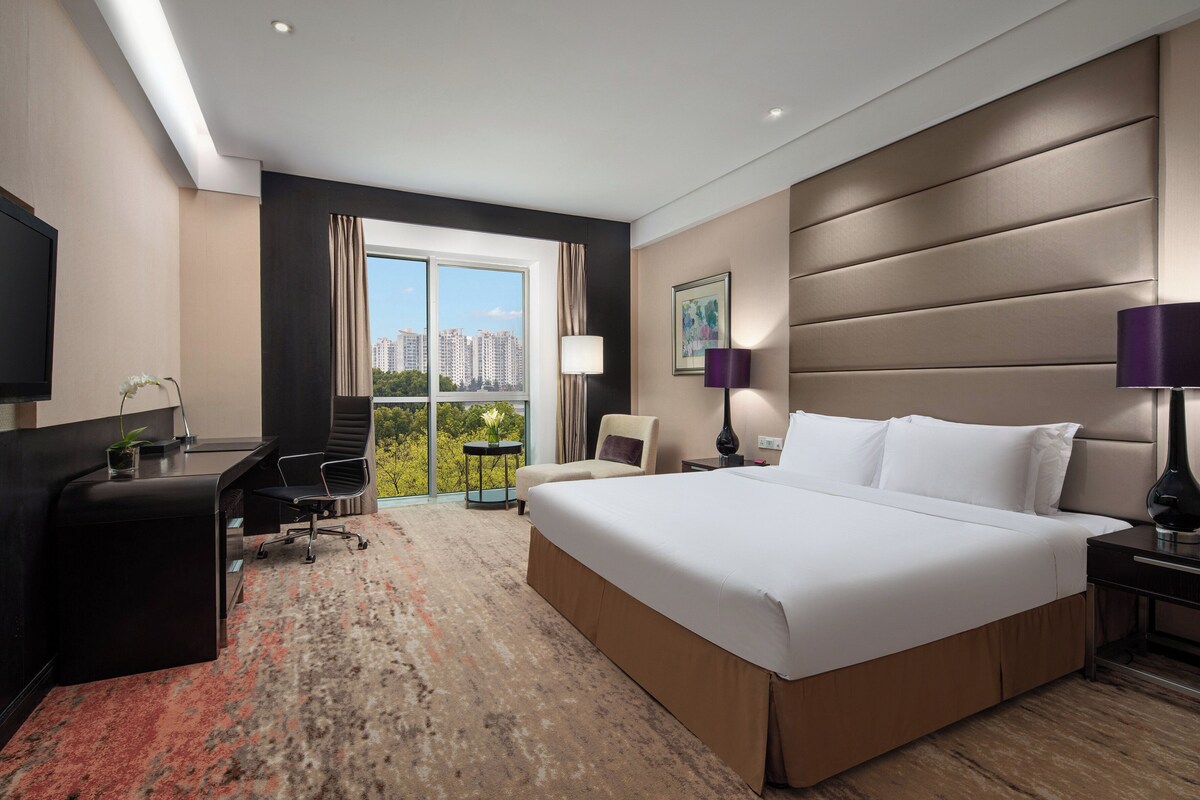 Una habitación de hotel moderna con una cama grande, un escritorio, una silla y un televisor.