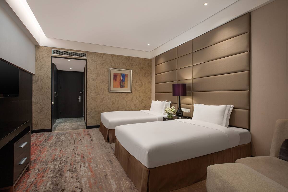 Habitació d'hotel amb dos llits, televisió, escriptori i una cadira.