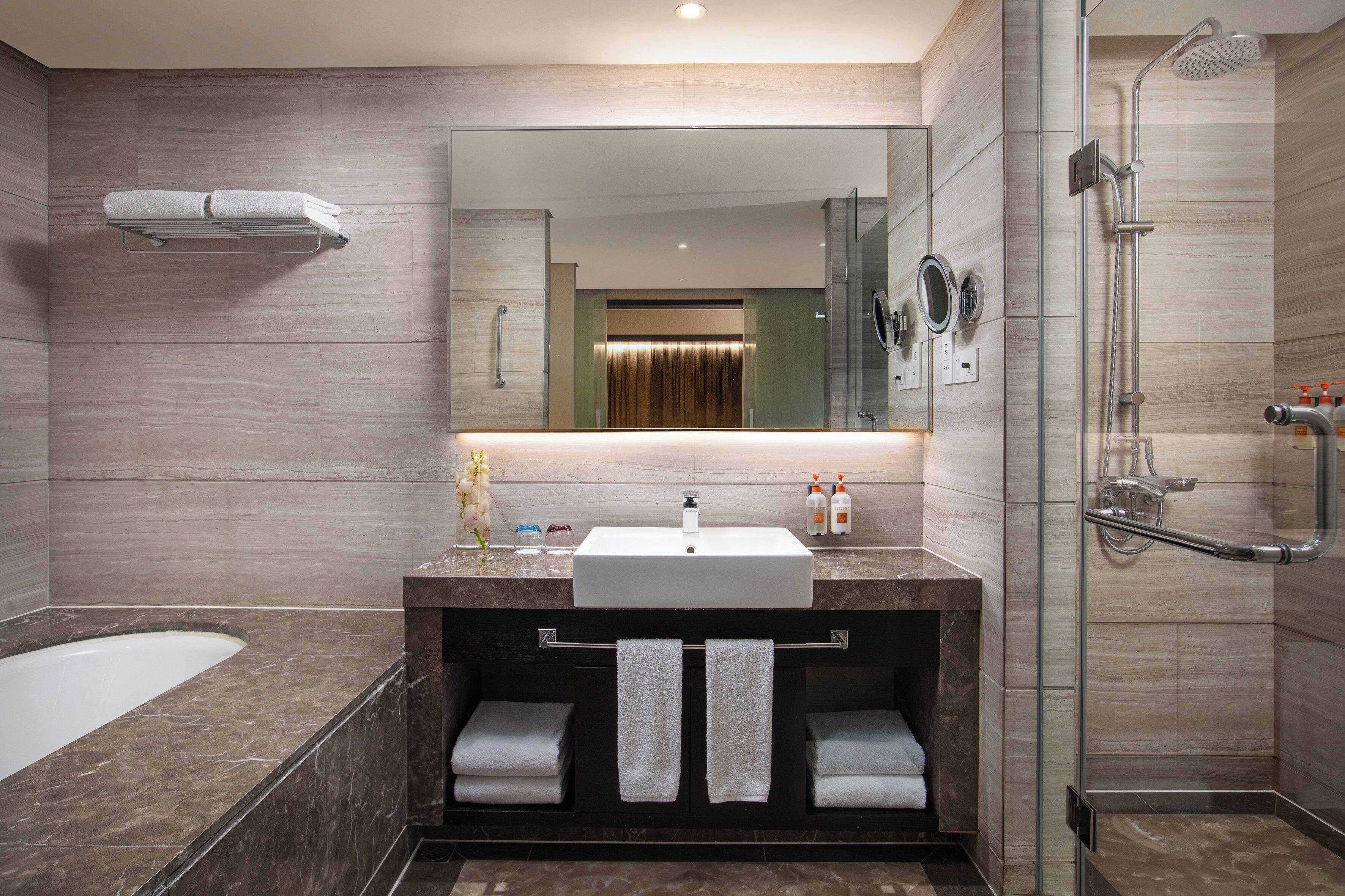 Een moderne badkamer met een grote spiegel, een badkuip, een douche en een wastafelmeubel met een wastafel en handdoekrek.