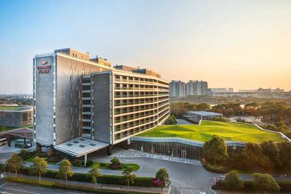 Un hotel moderno con una fachada curva, varios pisos y un césped cuidado.