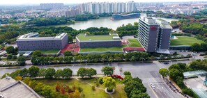 Un complejo moderno de edificios con varias estructuras, espacios verdes y un río al fondo.