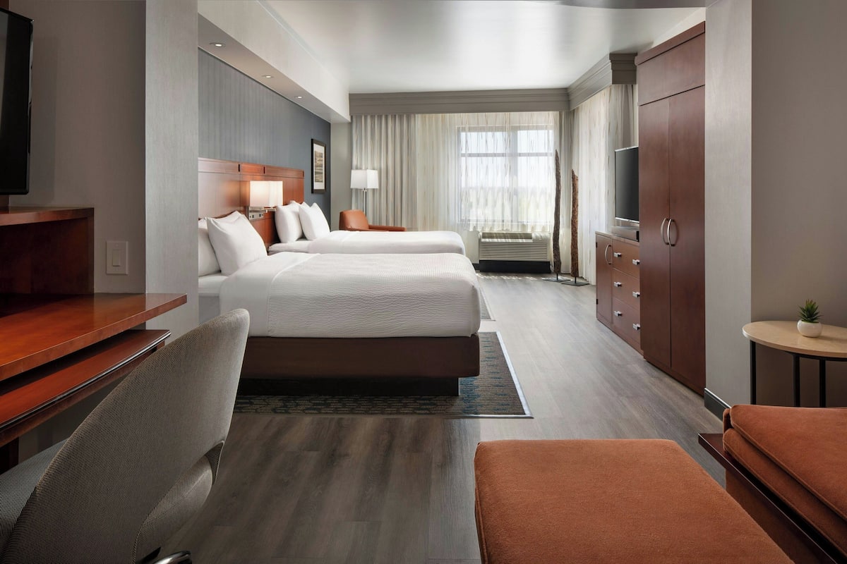 A hotel room with a large bed, a desk, a chair, a wardrobe, and a television.