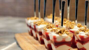 A row of dessert cups with a layered dessert, topped with granola, and served with black straws.
