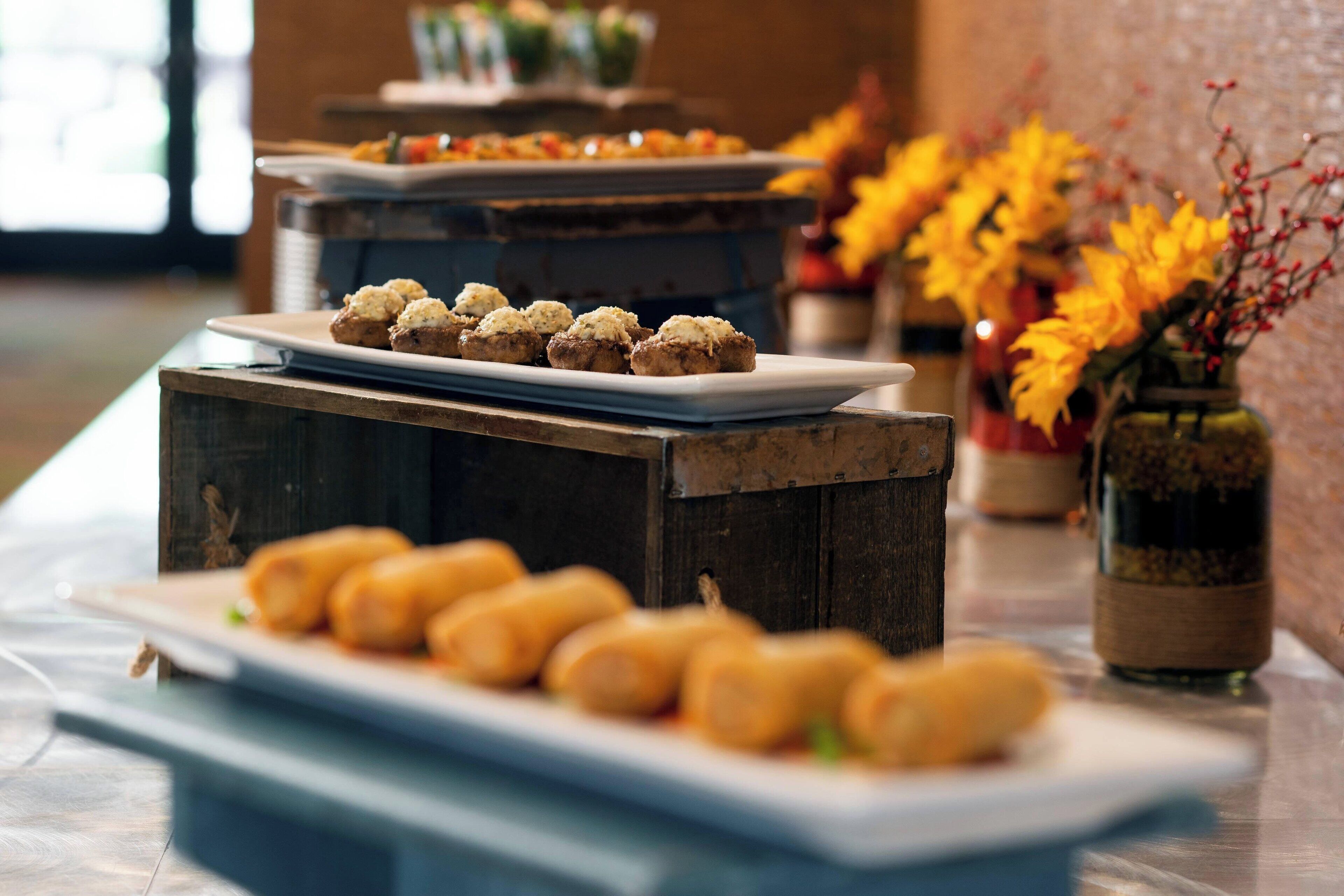 Una mesa de buffet con distintos platos, entre ellos pasteles y una botella de salsa.
