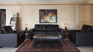 A living room with a black leather sofa, a coffee table, and a patterned rug. - Travelodge by Wyndham Kapuskasing (Kapuskasing)